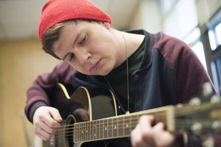Young man playing guitar in a red hat