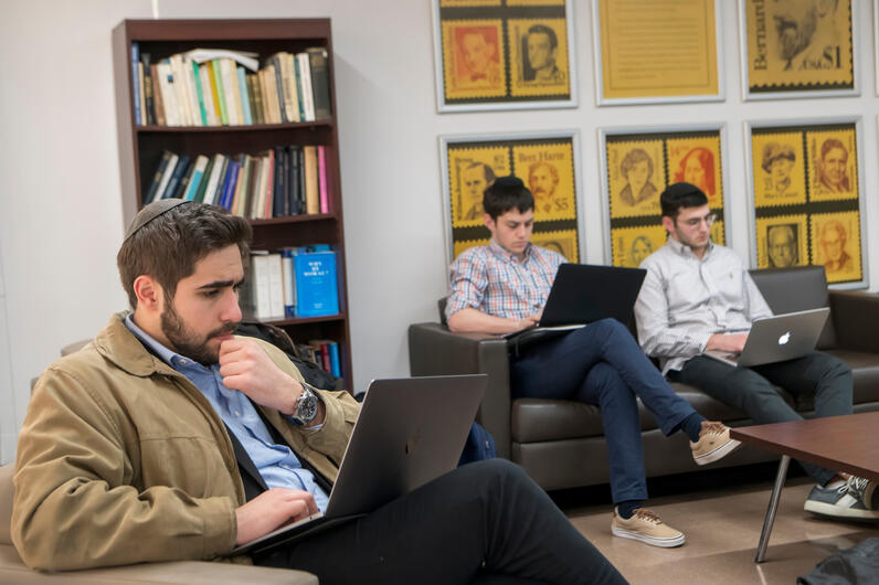 Male orthodox students with laptops in lounge