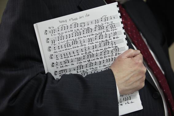 Sheet music held in a man's right arm